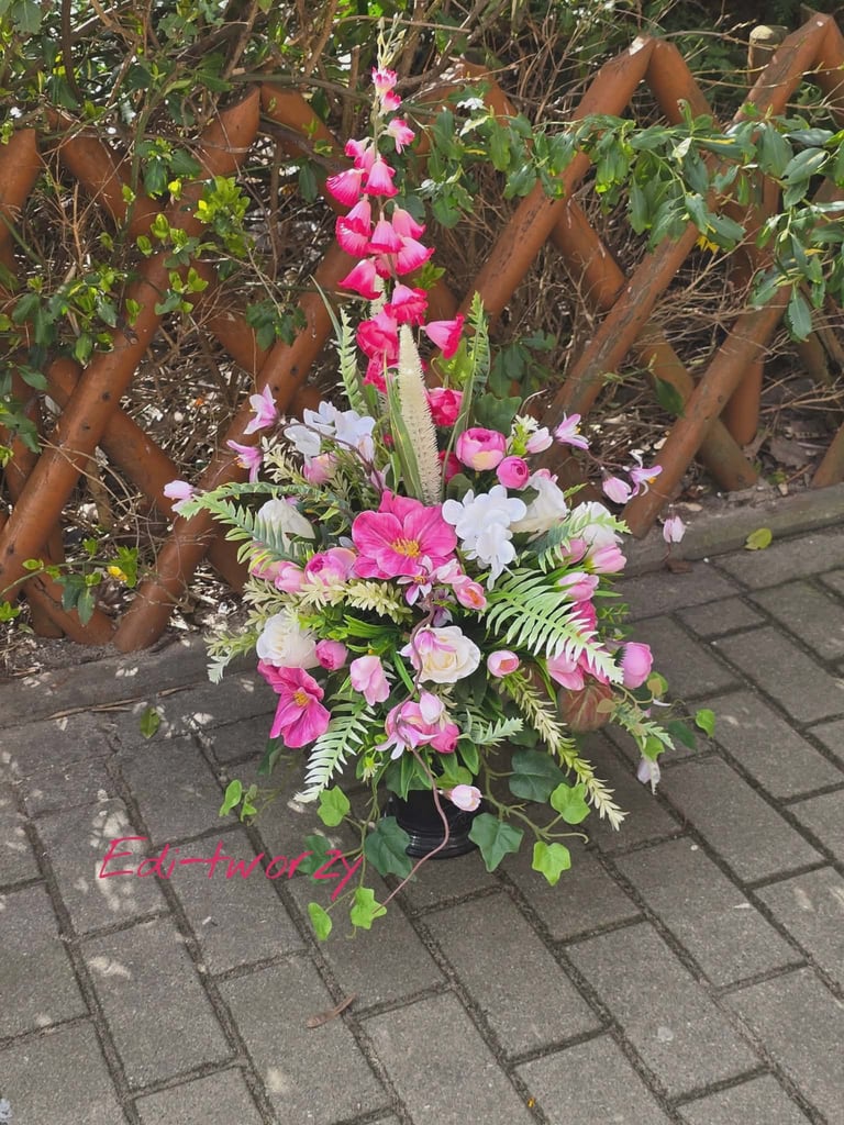Vibrant pink and white flower arrangement on patio against rust-colored lattice fence and green foliage