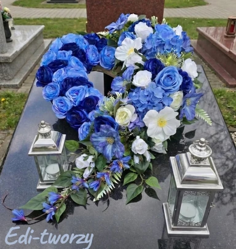 Blue and white floral arrangement with roses and hydrangeas on a grave with two white lanterns